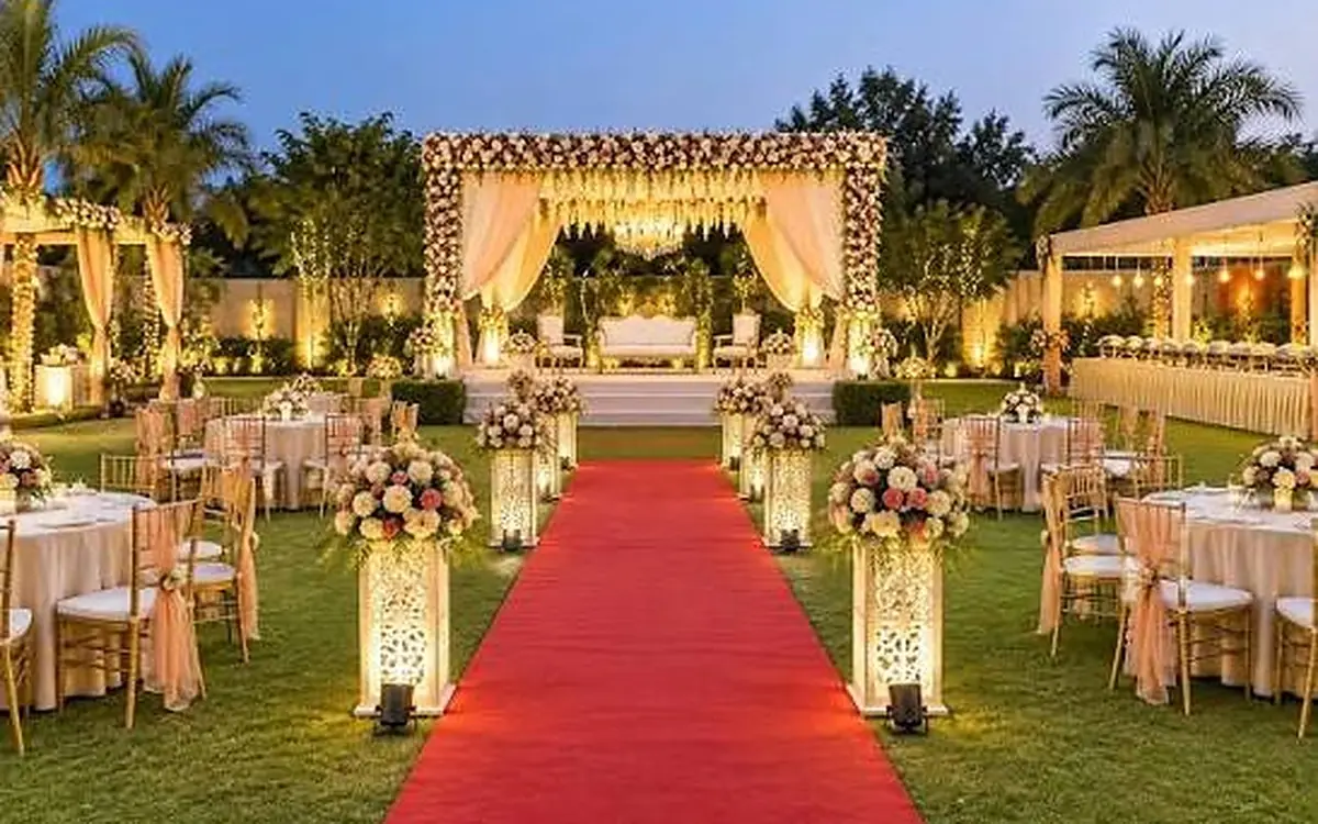 Wedding Transport Wedding venue lawn with a red carpet aisle, floral entrance arch and decorated tables at dusk